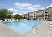Thumbnail 5 of 37 - A large swimming pool surrounded by lounge chairs and apartment buildings.