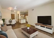 Thumbnail 1 of 37 - A living room with a white couch, a brown coffee table, and a flat screen TV.