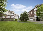 Thumbnail 34 of 37 - Apartment complex with green grass in front.
