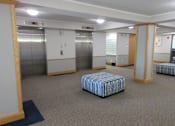 Thumbnail 28 of 37 - A room with a striped ottoman and two elevators.