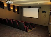 Thumbnail 25 of 37 - A movie theater with a large screen and red seats.