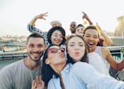 Thumbnail 2 of 2 - A group of friends are taking a selfie on a rooftop.
