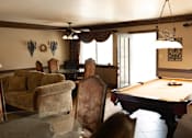 Thumbnail 3 of 38 - A pool table is in the middle of a room with a couch and chairs.