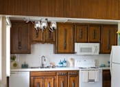 Thumbnail 15 of 38 - A kitchen with white appliances and wooden cabinets.