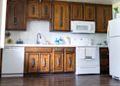 Thumbnail 14 of 38 - A kitchen with white appliances and wooden cabinets.