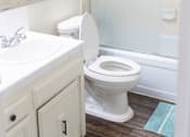 Thumbnail 33 of 38 - A white toilet in a bathroom with a white sink and a mirror.