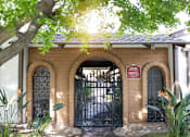 Thumbnail 4 of 38 - A black gate with a sign that says "No Parking" is in front of a brick building.