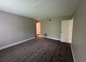 Thumbnail 13 of 18 - A room with a carpeted floor and a heater vent on the wall.