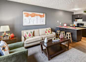Thumbnail 10 of 15 - A living room with a couch, a coffee table, and a painting on the wall.