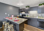 Thumbnail 14 of 15 - A kitchen with a granite countertop and bar stools.