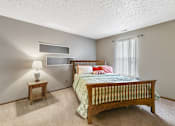 Thumbnail 13 of 15 - A bedroom with a bed, nightstand, and lamp.