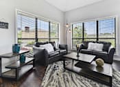 Thumbnail 7 of 15 - A living room with black leather couches and a coffee table with a vase and a baseball on it.