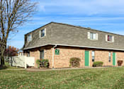 Thumbnail 20 of 20 - A small brick house with a green door and a white fence.