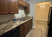 Thumbnail 15 of 18 - A kitchen with brown cabinets and a black dishwasher.