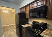 Thumbnail 10 of 18 - A kitchen with black appliances and wooden cabinets.
