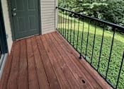Thumbnail 12 of 18 - A wooden deck with a green door and a black railing.