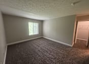 Thumbnail 14 of 18 - A room with a carpeted floor and a window with blinds.