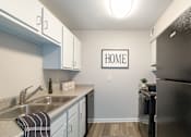 Thumbnail 3 of 18 - A kitchen with a black refrigerator and a sign that says "HOME".