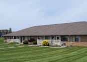 Thumbnail 15 of 20 - A house with a brown roof and a green lawn in front.