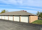Thumbnail 3 of 20 - A building with a brown roof and white garage doors.