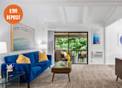 Thumbnail 1 of 23 - A living room with a blue sofa and a poster on the wall.