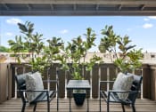 Thumbnail 46 of 57 - a patio with two chairs and a table on a balcony with trees in the background