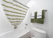 Thumbnail 18 of 41 - a bathroom with a white toilet and a green and white striped shower curtain