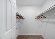 Thumbnail 19 of 24 - a walk in closet with two hanging racks and a white door