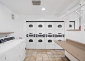Thumbnail 40 of 41 - a laundry room with white cabinets and a row of white washing machines