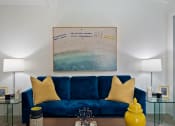 Thumbnail 2 of 24 - a living room with a blue couch and a painting on the wall
