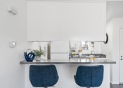 Thumbnail 10 of 68 - a kitchen with white cabinets and a counter with two blue chairs