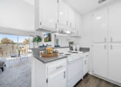 Thumbnail 7 of 68 - a white kitchen with white cabinetry and a counter top with a basket of fruit