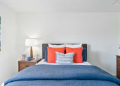 Thumbnail 12 of 68 - a bedroom with a blue bed and orange and blue pillows