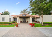 Thumbnail 23 of 24 - the view of the front entrance of a white building with potted plants and trees