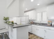 Thumbnail 27 of 68 - a white kitchen with white cabinets and a gray counter top