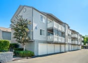 Thumbnail 61 of 68 - the view of an apartment building with garages and a tree