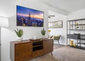 Thumbnail 6 of 32 - a living room with a desk and a wall mounted picture of a city skyline