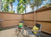 Thumbnail 13 of 32 - a patio with two chairs and a table in front of a fence