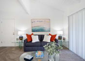 Thumbnail 5 of 34 - a living room with white walls and a dark blue couch with orange and white pillows