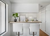 Thumbnail 52 of 61 - a kitchen with white cabinets and a counter with two white chairs