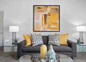 Thumbnail 32 of 61 - a living room with a gray couch with yellow pillows and a glass coffee table