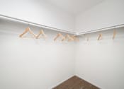 Thumbnail 38 of 61 - a walk in closet with white walls and wooden clothes hangers