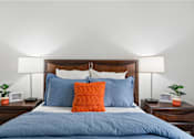 Thumbnail 7 of 41 - a bedroom with a bed with blue pillows and two nightstands with lamps