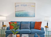 Thumbnail 16 of 19 - a living room with a blue couch and a painting on the wall