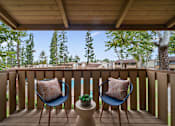 Thumbnail 13 of 41 - a balcony with two chairs and a view of a pool and trees