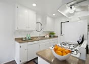 Thumbnail 9 of 19 - a white kitchen with a bowl of fruit on the counter
