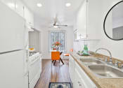 Thumbnail 3 of 19 - a kitchen with white appliances and counters and a table with a chair