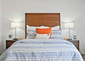 Thumbnail 6 of 19 - a bedroom with a bed with blue and white bedding and an orange pillow