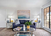 Thumbnail 3 of 28 - a living room with a blue couch and a coffee table with a plant on top of it