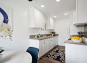Thumbnail 11 of 28 - a kitchen with white cabinets and a blue chair